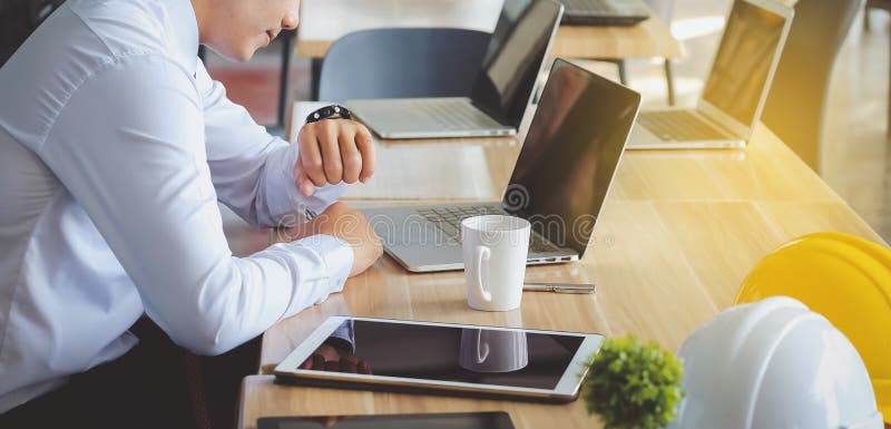 De jonge architecten die onderaan horloge kijken zijn van plan om wor te nemen stock fotografie De jonge architecten die onderaan horloge kijken zijn van plan om wor te nemen stock fotografie