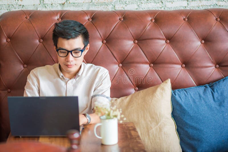 De jonge Aziatische mens het drinken koffie in koffie en het gebruiken van laptop verwerkt gegevens stock afbeeldingen De jonge Aziatische mens het drinken koffie in koffie en het gebruiken van laptop verwerkt gegevens stock afbeeldingen