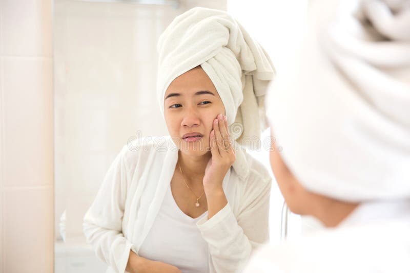 De jonge Aziatische vrouw die haar gezicht, het proberen drukken verwijdert acne stock afbeelding De jonge Aziatische vrouw die haar gezicht, het proberen drukken verwijdert acne stock afbeelding