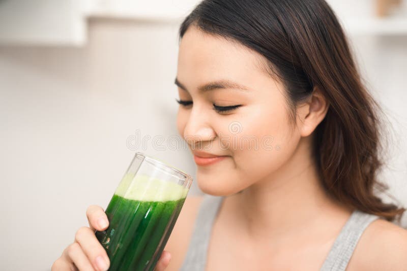 De jonge Aziatische vrouw geniet van gezonde vegetariër smoothie voor gewicht l stock afbeelding De jonge Aziatische vrouw geniet van gezonde vegetariër smoothie voor gewicht l stock afbeelding