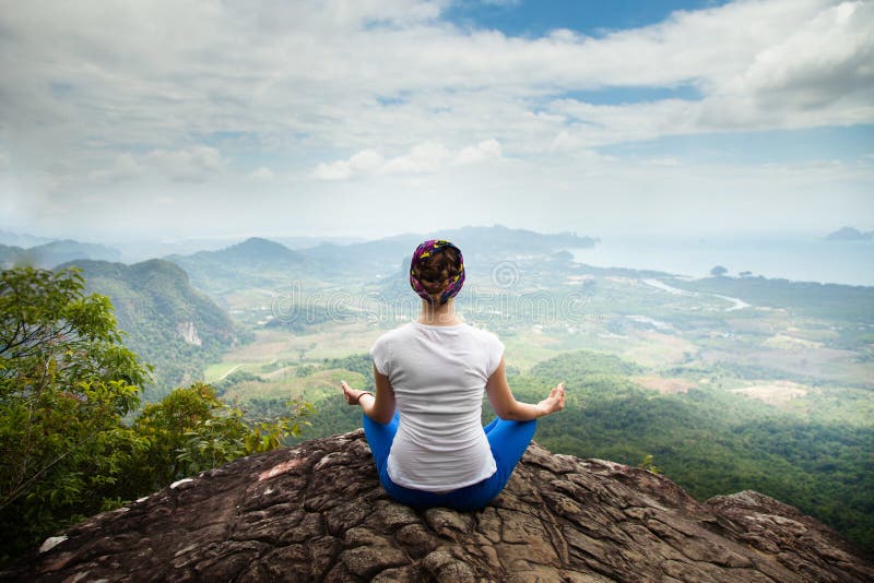 De de jonge blondevrouw het praktizeren yoga en meditatie in bergen tijdens luxeyoga gaan in Bali, Azië terug