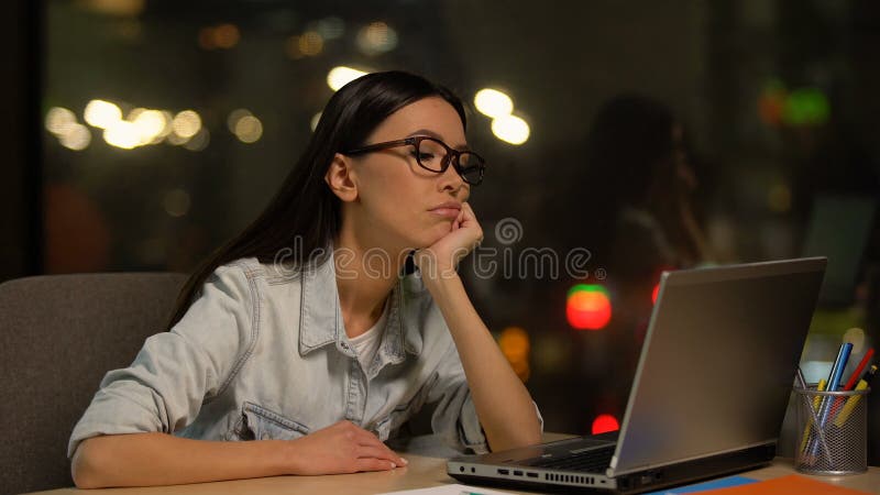 De jonge bored vrouw het werken aan laptop in bureau, die motivatie niet hebben, unloved baan