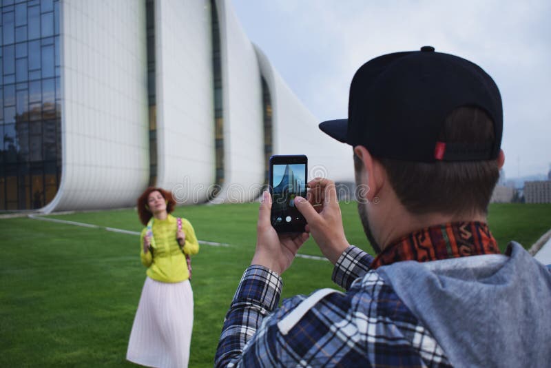 De jonge de paarvrouw en man maken foto op de mobiele telefoon in Baku Moderne hipsterman en vrouw die mobiele telefoon met behul royalty-vrije stock fotografie De jonge de paarvrouw en man maken foto op de mobiele telefoon in Baku Moderne hipsterman en vrouw die mobiele telefoon met behul royalty-vrije stock fotografie