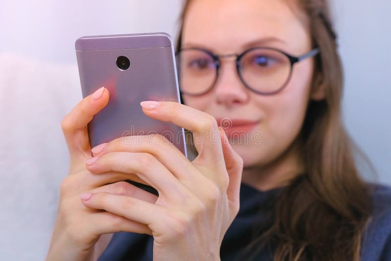 De jonge donkerbruine vrouw in glazen typt een bericht op een mobiele telefoon royalty-vrije stock fotografie De jonge donkerbruine vrouw in glazen typt een bericht op een mobiele telefoon royalty-vrije stock fotografie