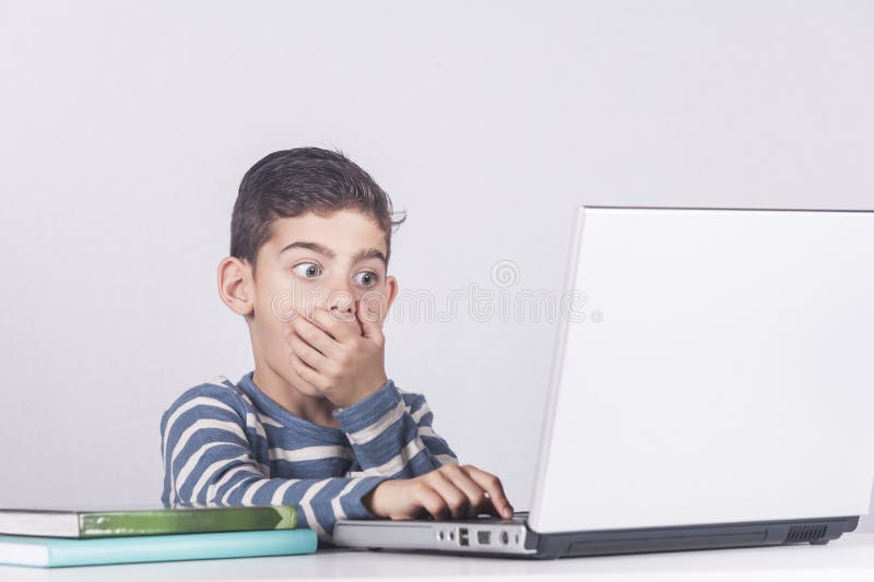 Young boy reacts while using a laptop. Internet safety for kids concept. Young boy reacts while using a laptop. Internet safety for kids concept