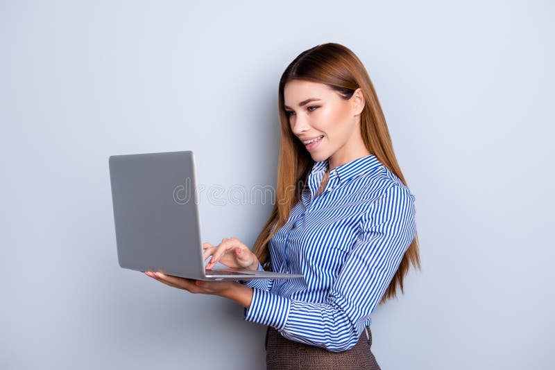 De jonge leuke bedrijfsdame houdt laptop en typt op het zij stock afbeeldingen De jonge leuke bedrijfsdame houdt laptop en typt op het zij stock afbeeldingen