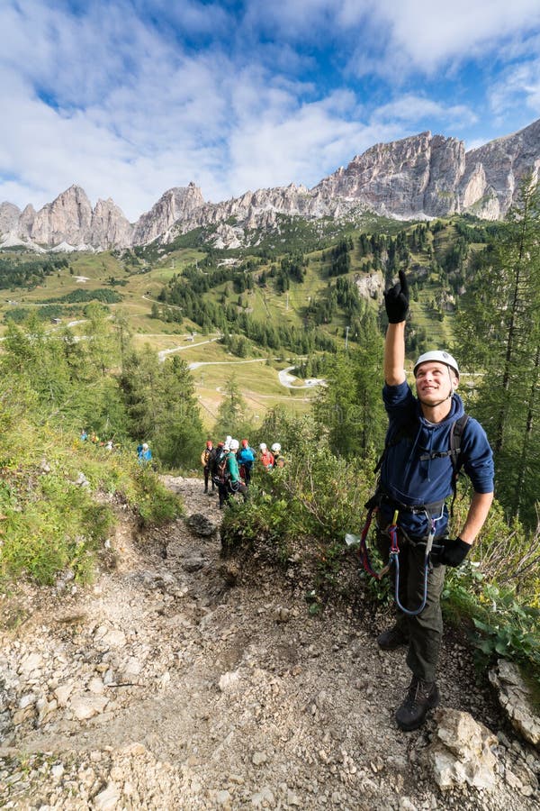 De jonge mannelijke klimmer bekijkt omhoog a via Ferrata in het Dolomiet en vele mensen bevinden zich achter hem stock foto De jonge mannelijke klimmer bekijkt omhoog a via Ferrata in het Dolomiet en vele mensen bevinden zich achter hem stock foto