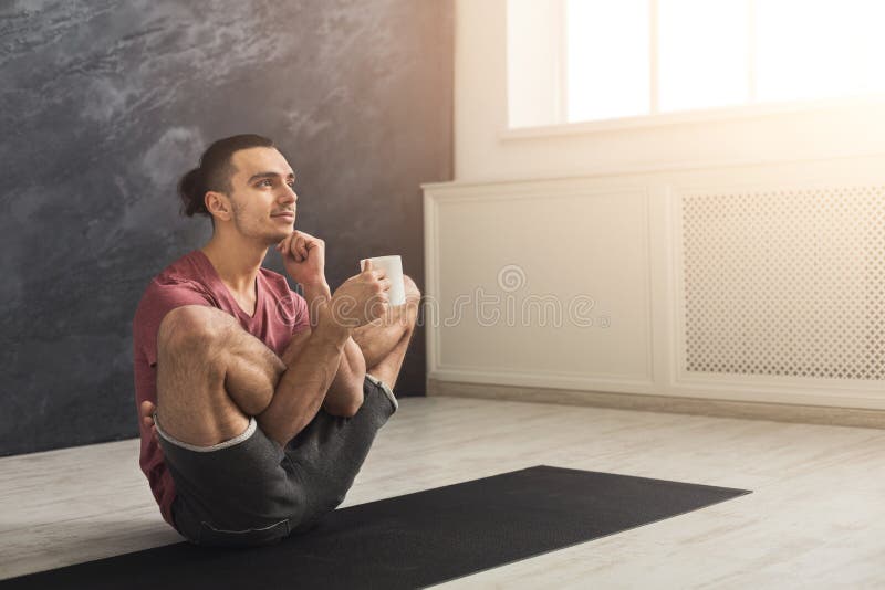 De jonge mens in flexibele yoga stelt het drinken thee royalty-vrije stock fotografie De jonge mens in flexibele yoga stelt het drinken thee royalty-vrije stock fotografie