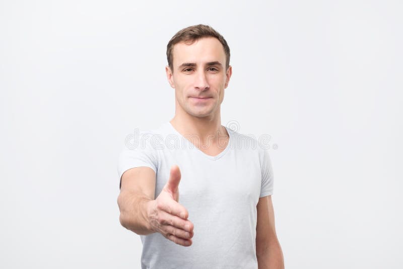 De jonge mens geeft handdruk, begroet met iemand, verheugt zich vergadering stock foto De jonge mens geeft handdruk, begroet met iemand, verheugt zich vergadering stock foto