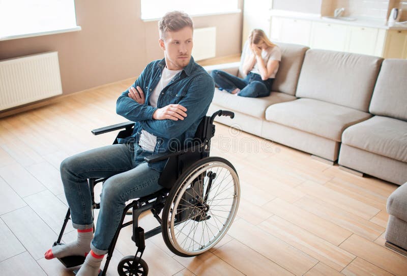 De jonge mens met inclusiviteit en de onbekwaamheid zitten op rolstoel vooraan Overhandigt gekruist en verstoord De jonge vrouw z royalty-vrije stock foto De jonge mens met inclusiviteit en de onbekwaamheid zitten op rolstoel vooraan Overhandigt gekruist en verstoord De jonge vrouw z royalty-vrije stock foto