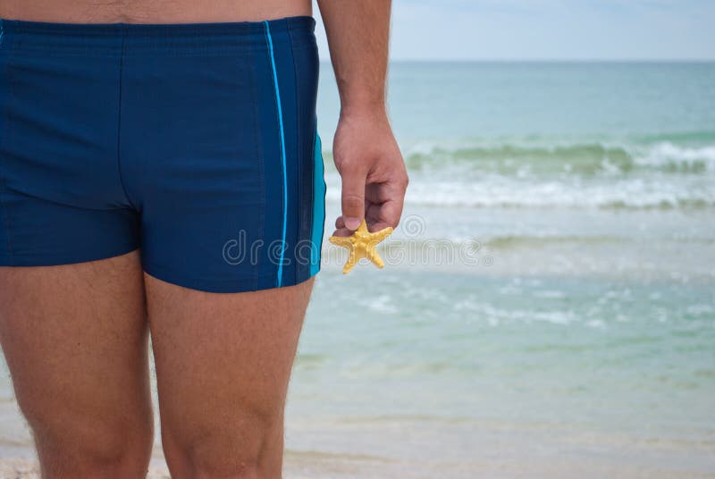 De jonge mensentribunes tegen de van het overzeese van het zandgolven kuststrand het waterhorizon houdt in zijn hand gele zeester stock afbeeldingen De jonge mensentribunes tegen de van het overzeese van het zandgolven kuststrand het waterhorizon houdt in zijn hand gele zeester stock afbeeldingen