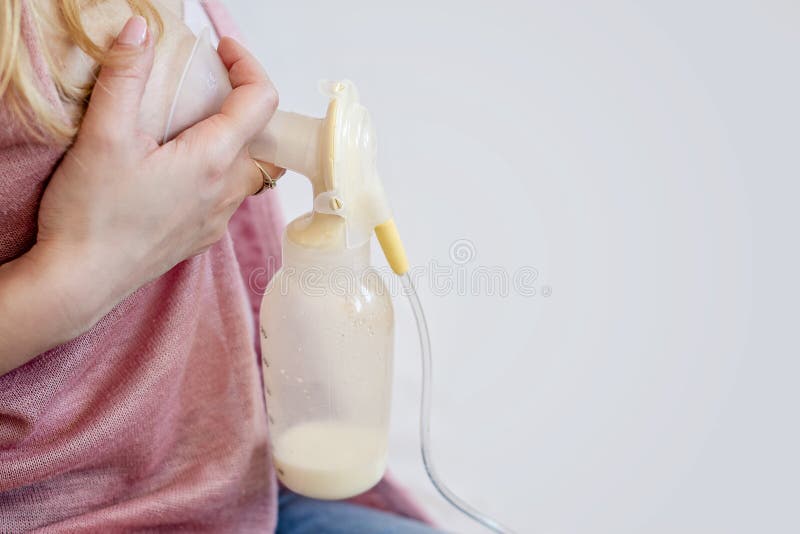 De jonge moeder gebruikt enige elektrische moedermelkpomp en pompt moedermelk voor haar baby Moedermelk voor het supplementaire v De jonge moeder gebruikt enige elektrische moedermelkpomp en pompt moedermelk voor haar baby Moedermelk voor het supplementaire v