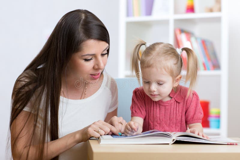 De jonge moeder leest een boek aan haar kinddochter royalty-vrije stock afbeeldingen De jonge moeder leest een boek aan haar kinddochter royalty-vrije stock afbeeldingen