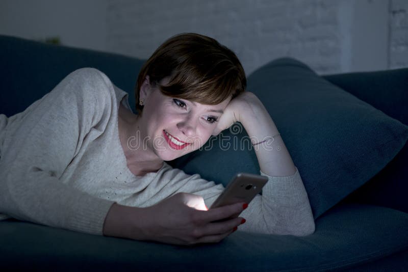 De jonge mooie en gelukkige rode haarvrouw op haar jaren '20 of jaren '30 die op huis liggen gaat liggen of bed gebruikend mobiel stock foto's De jonge mooie en gelukkige rode haarvrouw op haar jaren '20 of jaren '30 die op huis liggen gaat liggen of bed gebruikend mobiel stock foto's