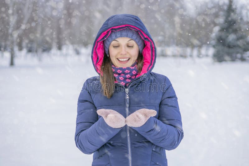 De jonge mooie glimlachende vrouw vangt sneeuwvlokken door handen De winter sneeuwweer royalty-vrije stock foto De jonge mooie glimlachende vrouw vangt sneeuwvlokken door handen De winter sneeuwweer royalty-vrije stock foto
