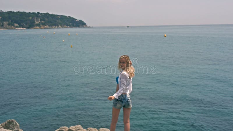 De jonge mooie mannequinvrouw heft omhoog haar wapens op het strand op