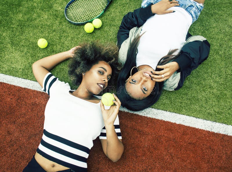 De jonge mooie meisjes die op tennisbaan hangen, vormen gekleed modieus swag, het beste vrienden gelukkige samen glimlachen stock foto De jonge mooie meisjes die op tennisbaan hangen, vormen gekleed modieus swag, het beste vrienden gelukkige samen glimlachen stock foto