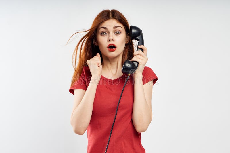 De jonge mooie vrouw op witte achtergrond in rode kleding houdt landline telefoon, emoties stock foto De jonge mooie vrouw op witte achtergrond in rode kleding houdt landline telefoon, emoties stock foto