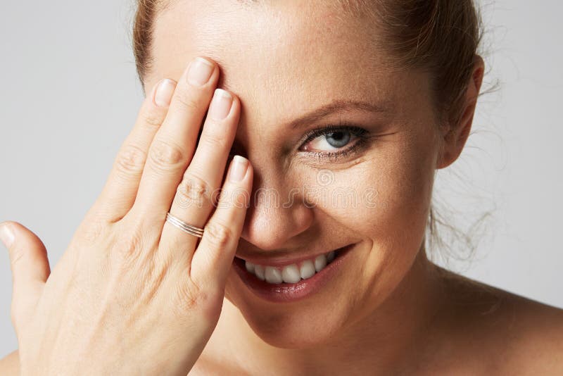 De jonge mooie vrouwen met blondehaar bevestigden erachter, grote ogen, en het naakte schouders glimlachen van en het sluiten haa stock afbeelding De jonge mooie vrouwen met blondehaar bevestigden erachter, grote ogen, en het naakte schouders glimlachen van en het sluiten haa stock afbeelding