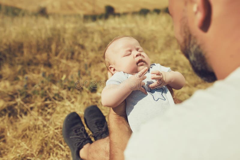 De jonge papa houdt een pasgeboren baby terwijl het lopen in aard de gelukkige vader draagt borrels en een t-shirt Internationale stock foto's De jonge papa houdt een pasgeboren baby terwijl het lopen in aard de gelukkige vader draagt borrels en een t-shirt Internationale stock foto's