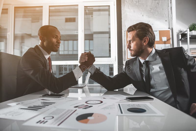 De jonge sterke managers concurreren op wapens stock afbeelding De jonge sterke managers concurreren op wapens stock afbeelding