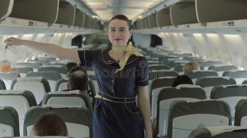 De jonge stewardess geeft de instructies over zuurstofmaskers