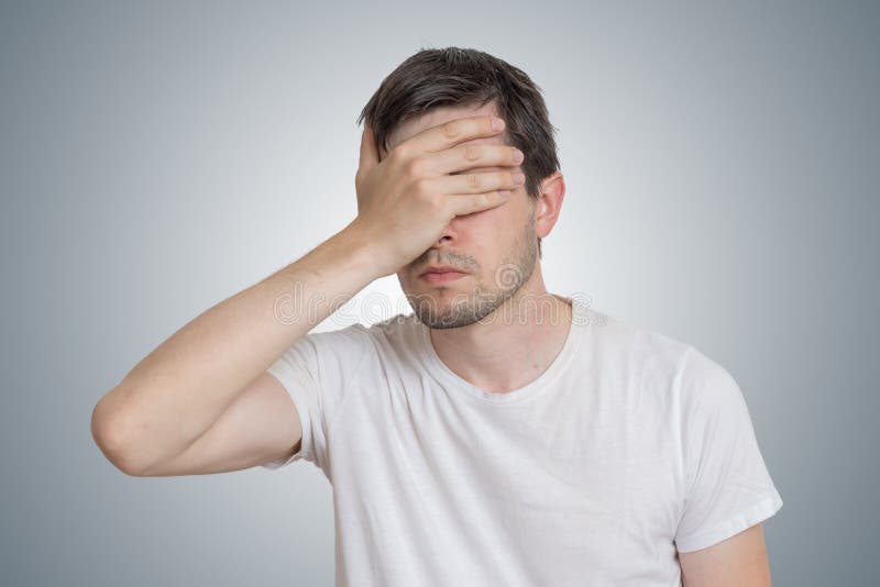 De jonge teleurgestelde mens behandelt zijn gezicht stock afbeelding De jonge teleurgestelde mens behandelt zijn gezicht stock afbeelding
