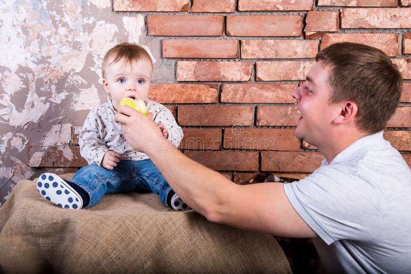 De jonge vader geeft zijn zoon een groene te eten appel r r royalty-vrije stock foto De jonge vader geeft zijn zoon een groene te eten appel r r royalty-vrije stock foto