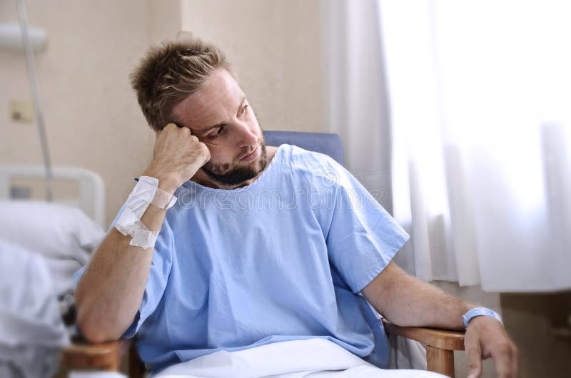 De jonge verwonde mens in de zitting van de het ziekenhuisruimte alleen in pijn maakte zich voor zijn gezondheidsvoorschrift onge stock fotografie De jonge verwonde mens in de zitting van de het ziekenhuisruimte alleen in pijn maakte zich voor zijn gezondheidsvoorschrift onge stock fotografie