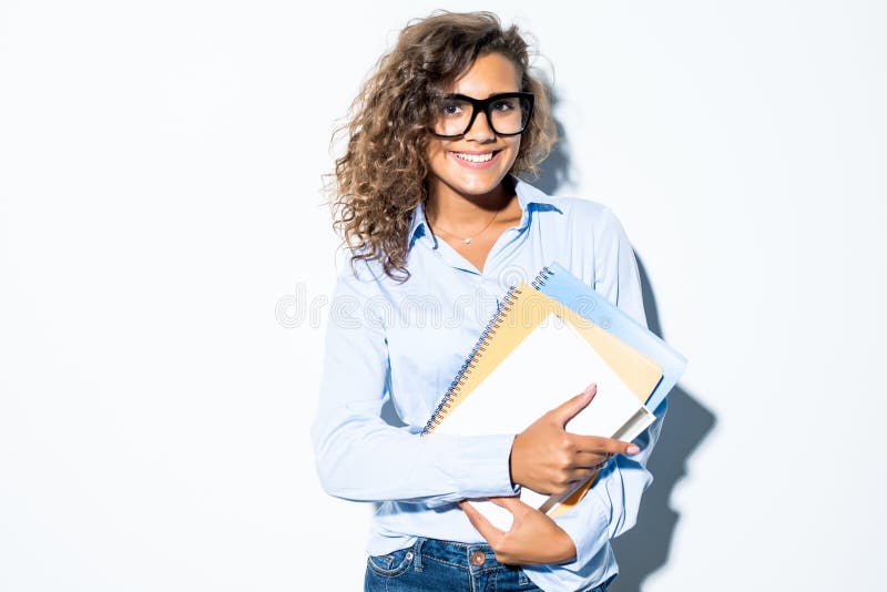 De jonge vriendschappelijke krullende Latijnse bedrijfsvrouw met boeken in handen isoleerde witte achtergrond