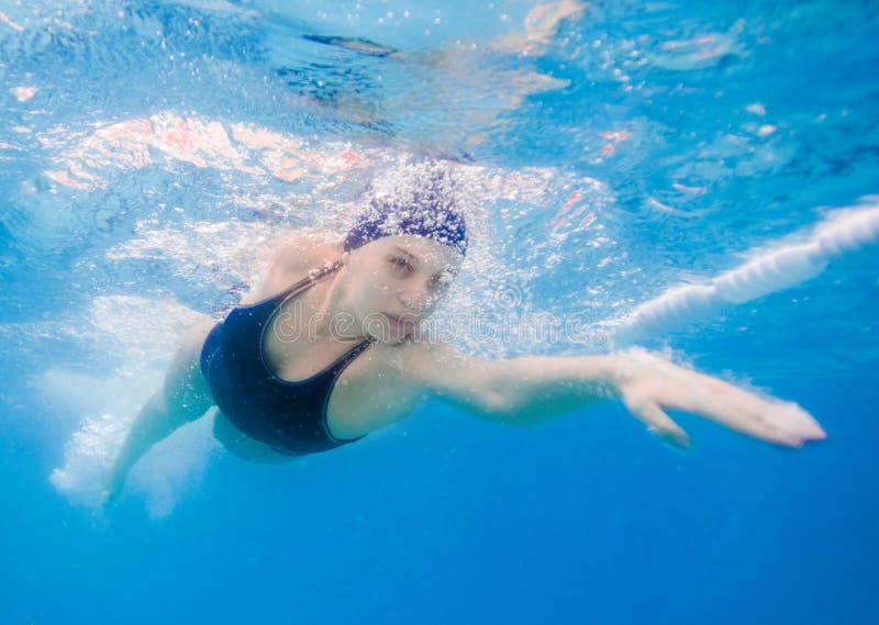 De jonge vrouw die de voorzijde zwemmen kruipt in een pool, genomen onderwater