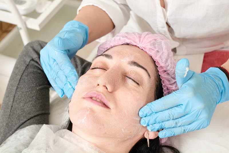 De jonge vrouw doet professionele gezichtsmassage in de schoonheidssalon stock afbeeldingen De jonge vrouw doet professionele gezichtsmassage in de schoonheidssalon stock afbeeldingen