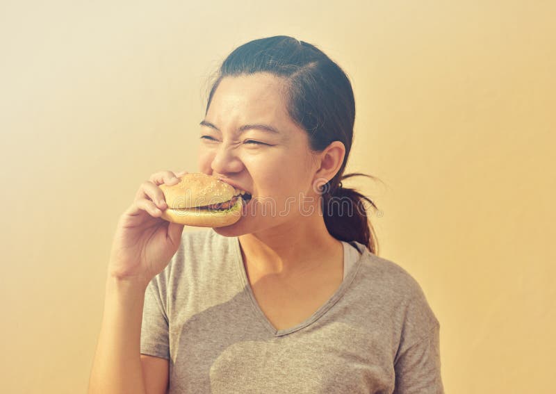 De jonge vrouw eet ter beschikking ongezonde kosthamburger royalty-vrije stock foto's De jonge vrouw eet ter beschikking ongezonde kosthamburger royalty-vrije stock foto's