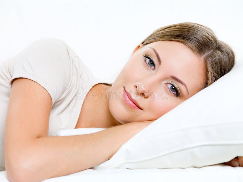 De jonge vrouw heeft een rust op het bed stock afbeelding De jonge vrouw heeft een rust op het bed stock afbeelding