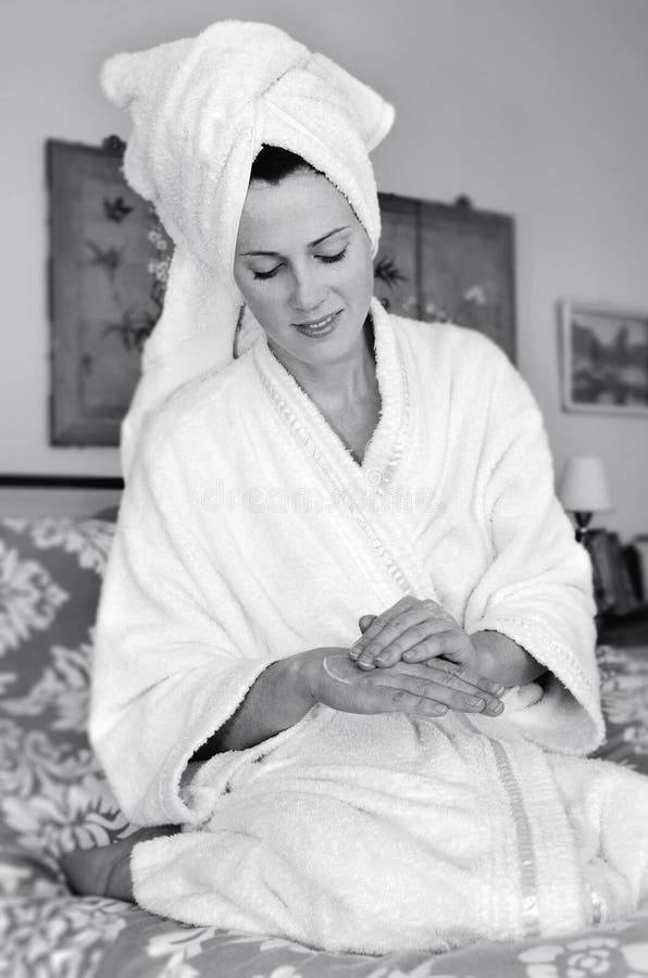 De jonge vrouw is moisturiser op haar huid van toepassing stock foto De jonge vrouw is moisturiser op haar huid van toepassing stock foto