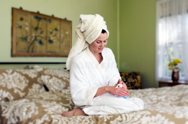 De jonge vrouw is moisturiser op haar huid van toepassing stock foto's De jonge vrouw is moisturiser op haar huid van toepassing stock foto's