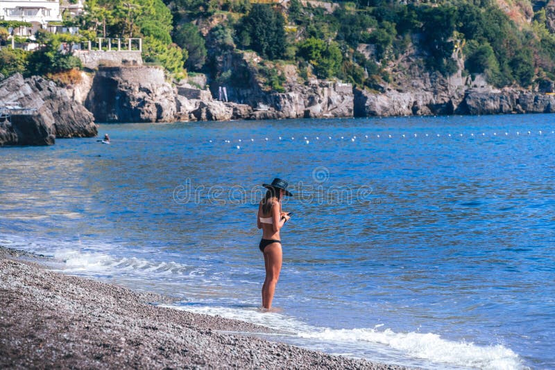 De jonge vrouw status alleen bij strand en bekijkt haar telefoon Concepten goed, slecht signaal stock afbeelding De jonge vrouw status alleen bij strand en bekijkt haar telefoon Concepten goed, slecht signaal stock afbeelding