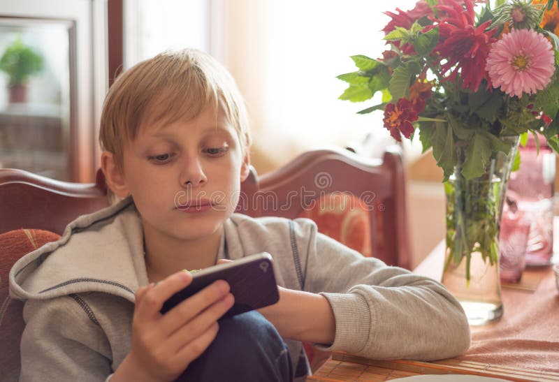 De jongen gebruikt thuis een smartphone stock foto De jongen gebruikt thuis een smartphone stock foto