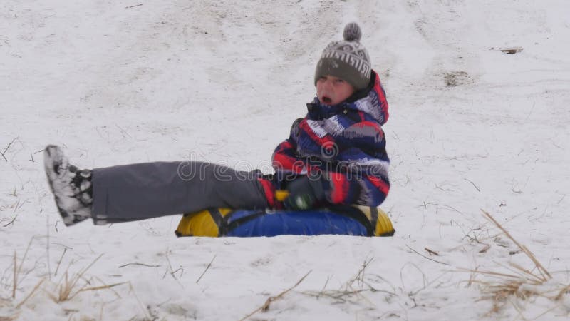 De jongen glijdt onderaan de berg in de sneeuw royalty-vrije stock afbeelding De jongen glijdt onderaan de berg in de sneeuw royalty-vrije stock afbeelding