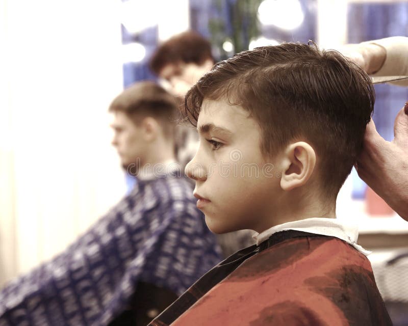 De jongen heeft zijn die haar in de mensenruimte van de kapperswinkel wordt gesneden royalty-vrije stock fotografie De jongen heeft zijn die haar in de mensenruimte van de kapperswinkel wordt gesneden royalty-vrije stock fotografie