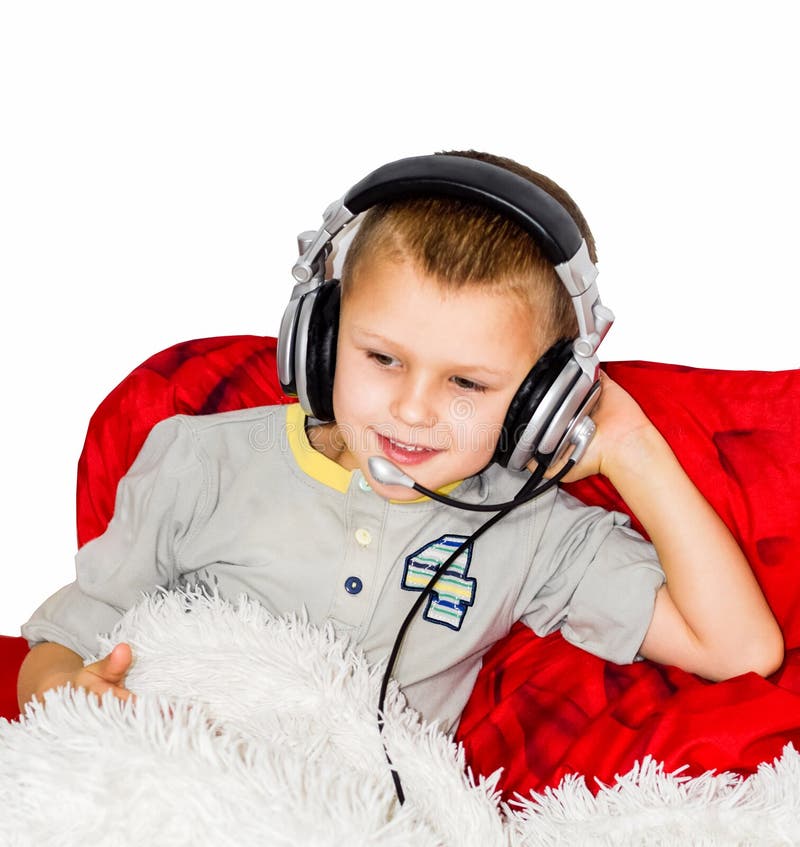 De jongen ligt op het bed en luistert aan muziek met hoofdtelefoons royalty-vrije stock afbeeldingen De jongen ligt op het bed en luistert aan muziek met hoofdtelefoons royalty-vrije stock afbeeldingen