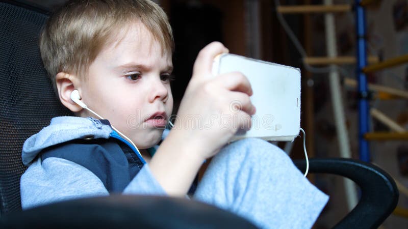 De jongen luistert aan muziek door hoofdtelefoons In de ruimte van de kinderen geniet het kind van muziek stock foto's De jongen luistert aan muziek door hoofdtelefoons In de ruimte van de kinderen geniet het kind van muziek stock foto's