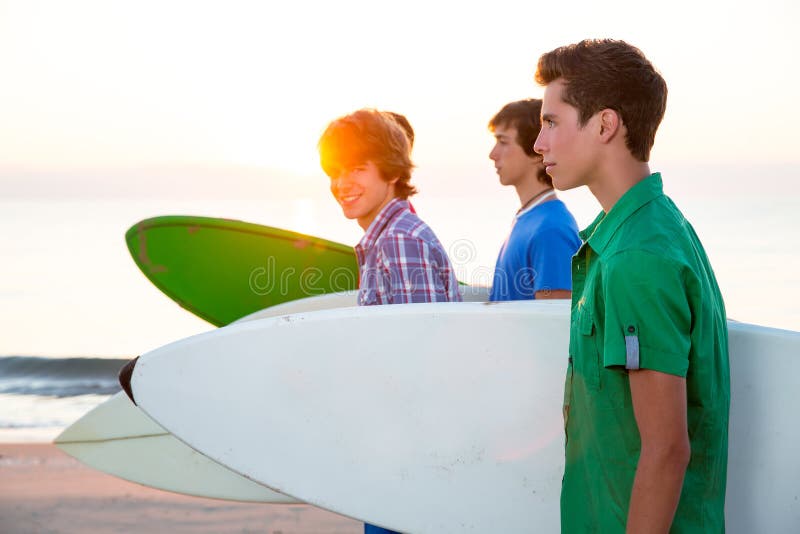 De jongens die van de surfertiener bij strandkust lopen royalty-vrije stock foto De jongens die van de surfertiener bij strandkust lopen royalty-vrije stock foto
