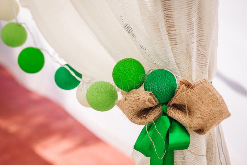 De katoenen ballenslinger hangt op een wit gordijn Heldere gekleurde decoratie Huwelijk stock fotografie De katoenen ballenslinger hangt op een wit gordijn Heldere gekleurde decoratie Huwelijk stock fotografie