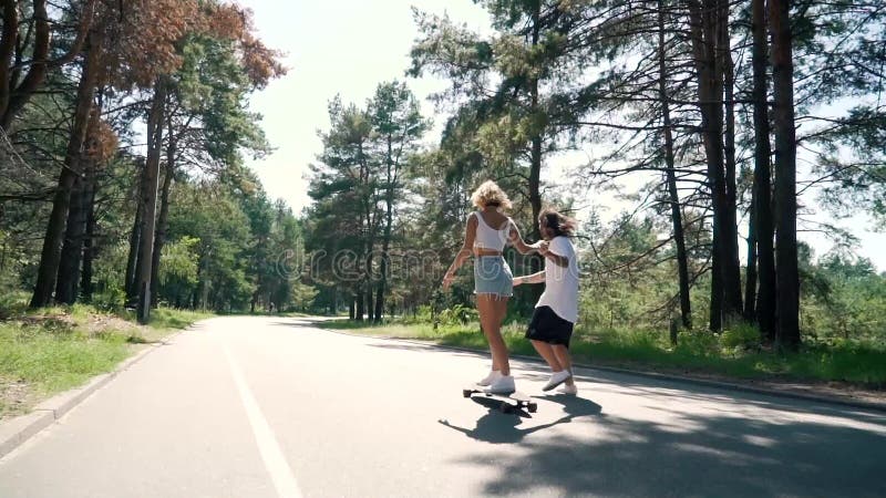 De kerel houdt de hand van het meisje wanneer zij een skateboard berijdt