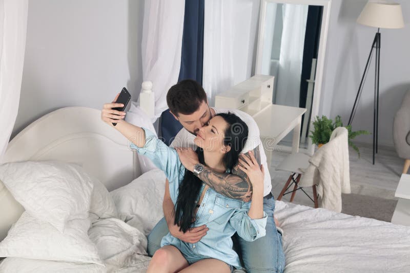 De kerel kust het meisje tot zij selfie maakt stock foto De kerel kust het meisje tot zij selfie maakt stock foto