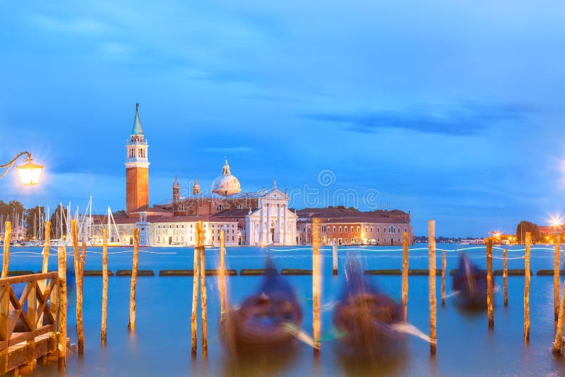 De kerk en de gondels van San Giorgio Maggiore in Venetië, Italië tijdens blauwe uurzonsopgang Nadruk op de kerk stock afbeeldingen De kerk en de gondels van San Giorgio Maggiore in Venetië, Italië tijdens blauwe uurzonsopgang Nadruk op de kerk stock afbeeldingen