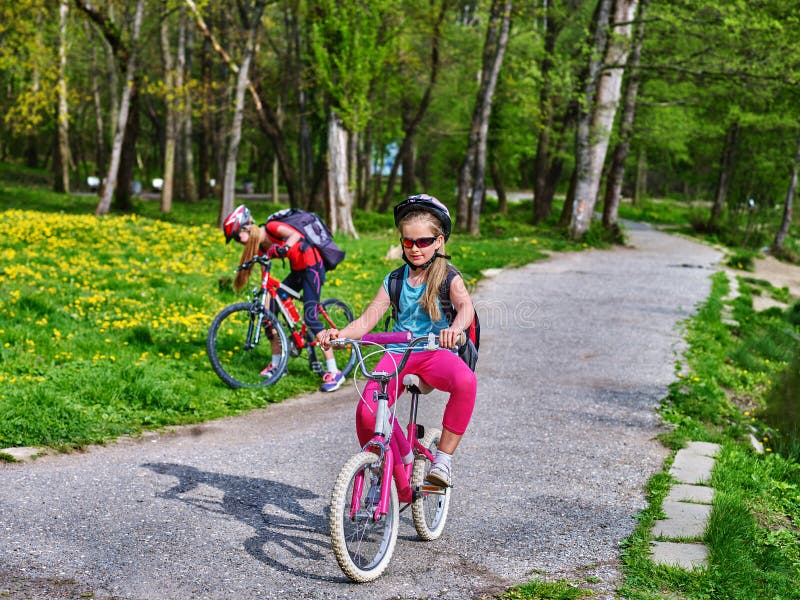 De kinderen berijden fiets op groen gras en bloemen in park royalty-vrije stock foto's De kinderen berijden fiets op groen gras en bloemen in park royalty-vrije stock foto's