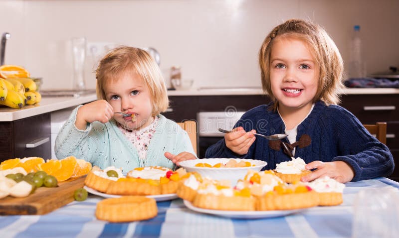 De kinderen eten cakes bij keuken royalty-vrije stock fotografie De kinderen eten cakes bij keuken royalty-vrije stock fotografie