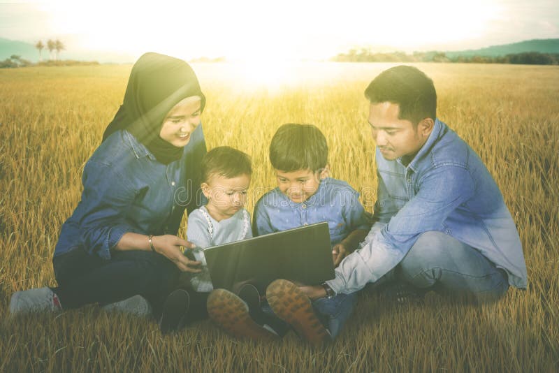 De kinderen gebruiken laptop met hun ouders in weide stock fotografie De kinderen gebruiken laptop met hun ouders in weide stock fotografie